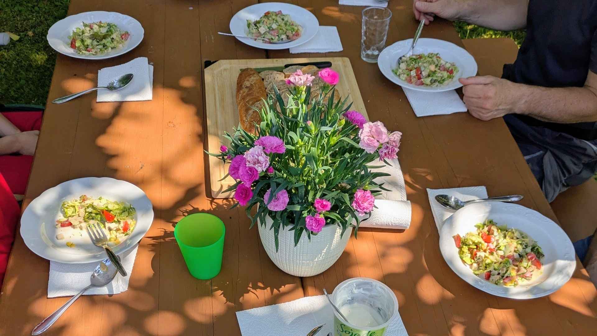 12-von-12-juli-2026-beitragsbild Ein gedeckter Tisch mit Blumen, Baguette, Salat auf weißen Suppentellern.