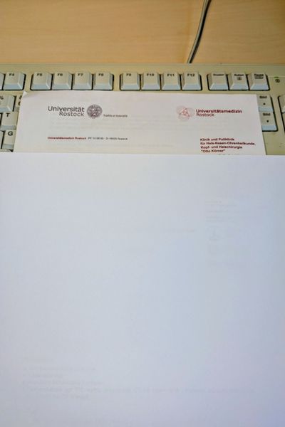 Ein Arztbrief der uni-Klinik Rostock liegt auf einer Tastatur. Persönliche Daten sind durch ein weißes Blatt abgedeckt.