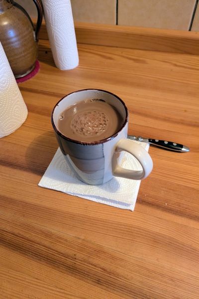 In einer Keramiktasse ist eine Carobmilch aufgegossen.