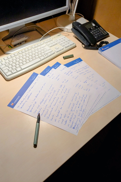 Handschriftliche Notizen liegen aufgefächert auf einem Schreibtisch.