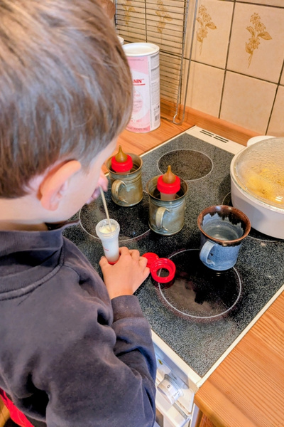 Ein Junge hilft, Katzenmilch anzurühren.